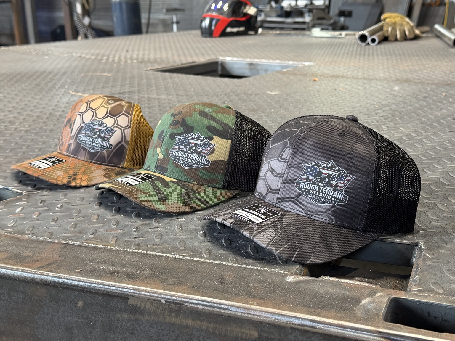 Rough Terrain Welding branded hats on a workshop table